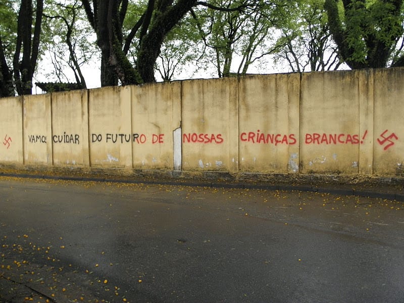 Muro pichado com as susticas e frase racista