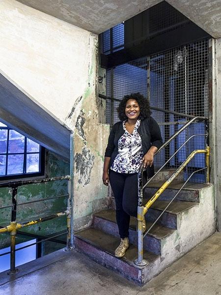 Silvana Bahia- mulher negra, de cabelo cacheado- em pé em uma escada