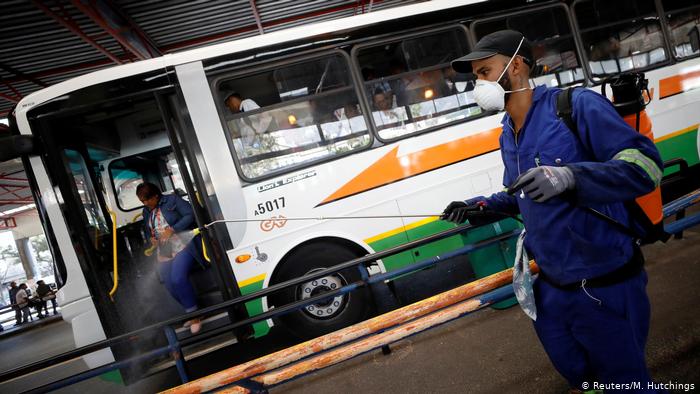 Foto de um homem pulverizando com produtos de limpeza uma estação de ônibus